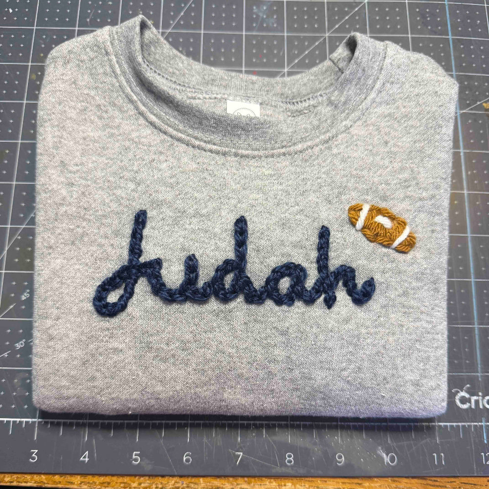 Folded gray toddler sweatshirt with the name 'Judah' and a football embroidered design